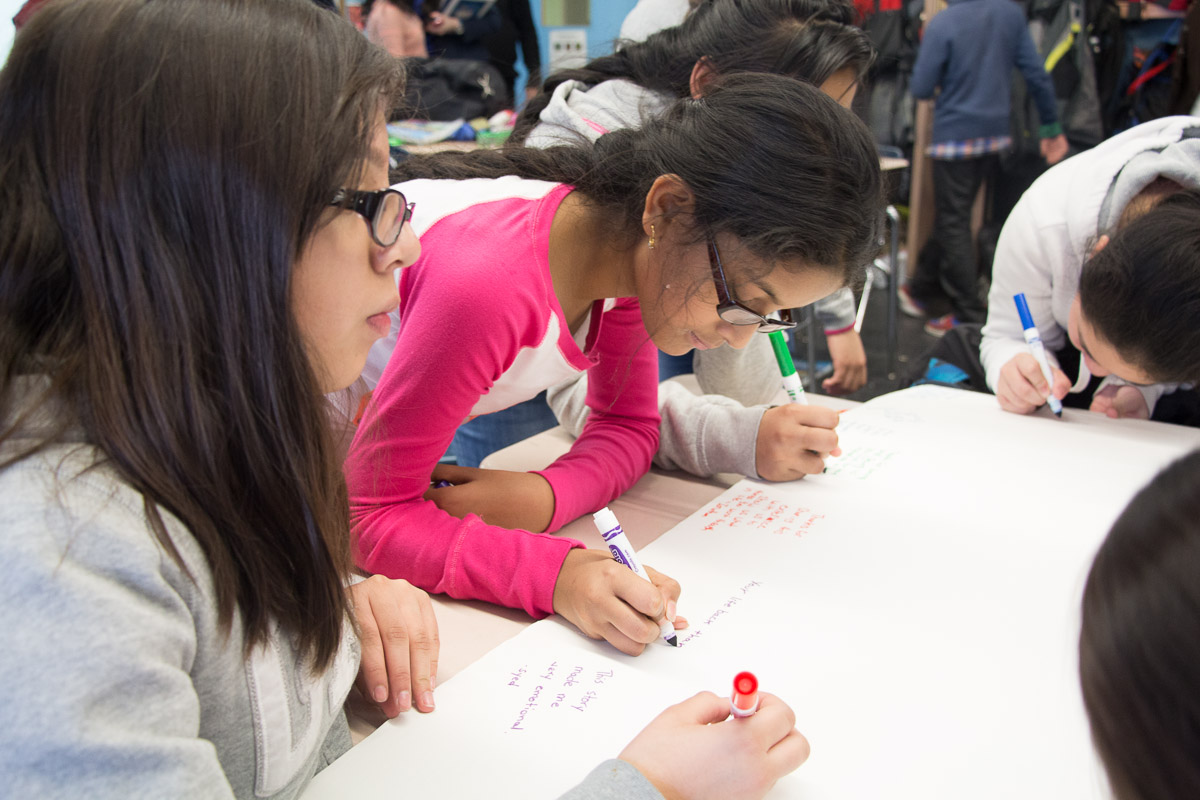 Sixth-grade students at Ditmas Juior High School write messages to visiting author Inge Auerbacher