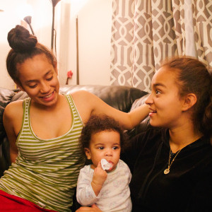 Fourteen-year-old Jovannitza Torres (left) and 15-year-old Jamie Torres (right) hang out with their niece at home in Stapleton, Staten Island.